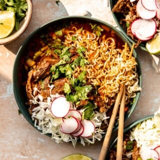 Bowl of birria ramen topped with shredded cabbage, sliced radishes and fresh cilantro.