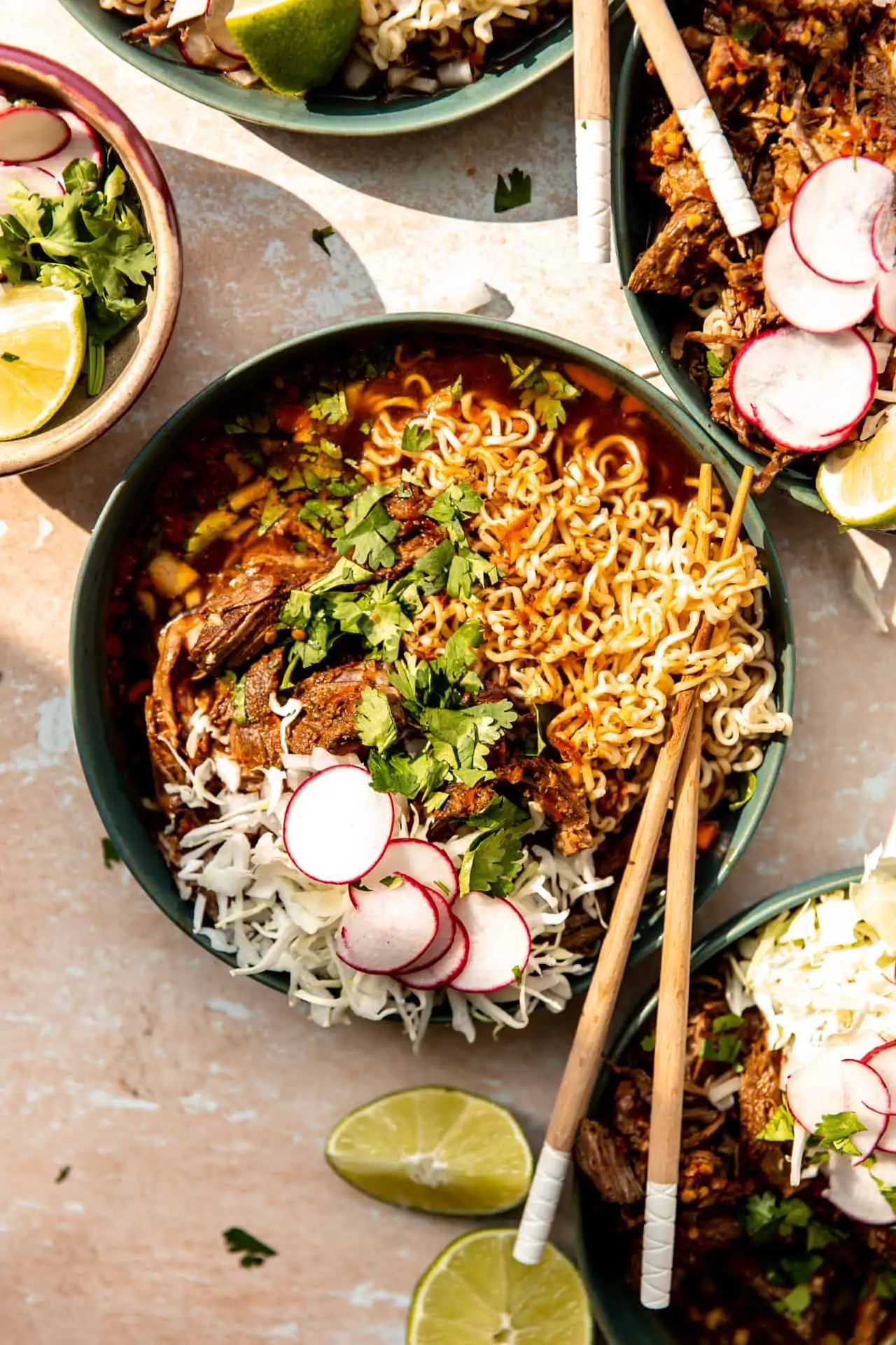 Bowl of birria ramen topped with shredded cabbage, sliced radishes and fresh cilantro.