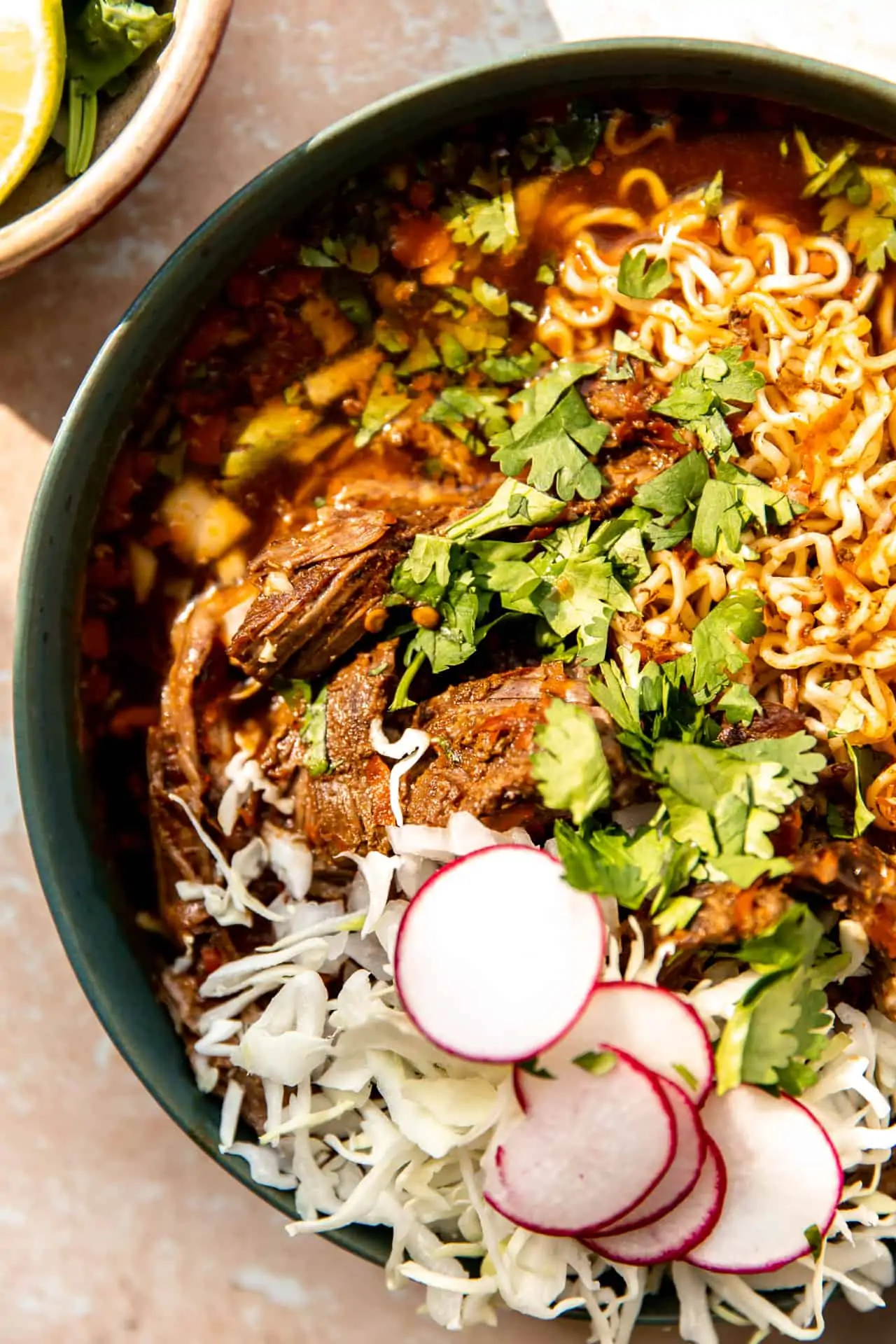 Close up view of chopped birria meat in a bowl of ramen.