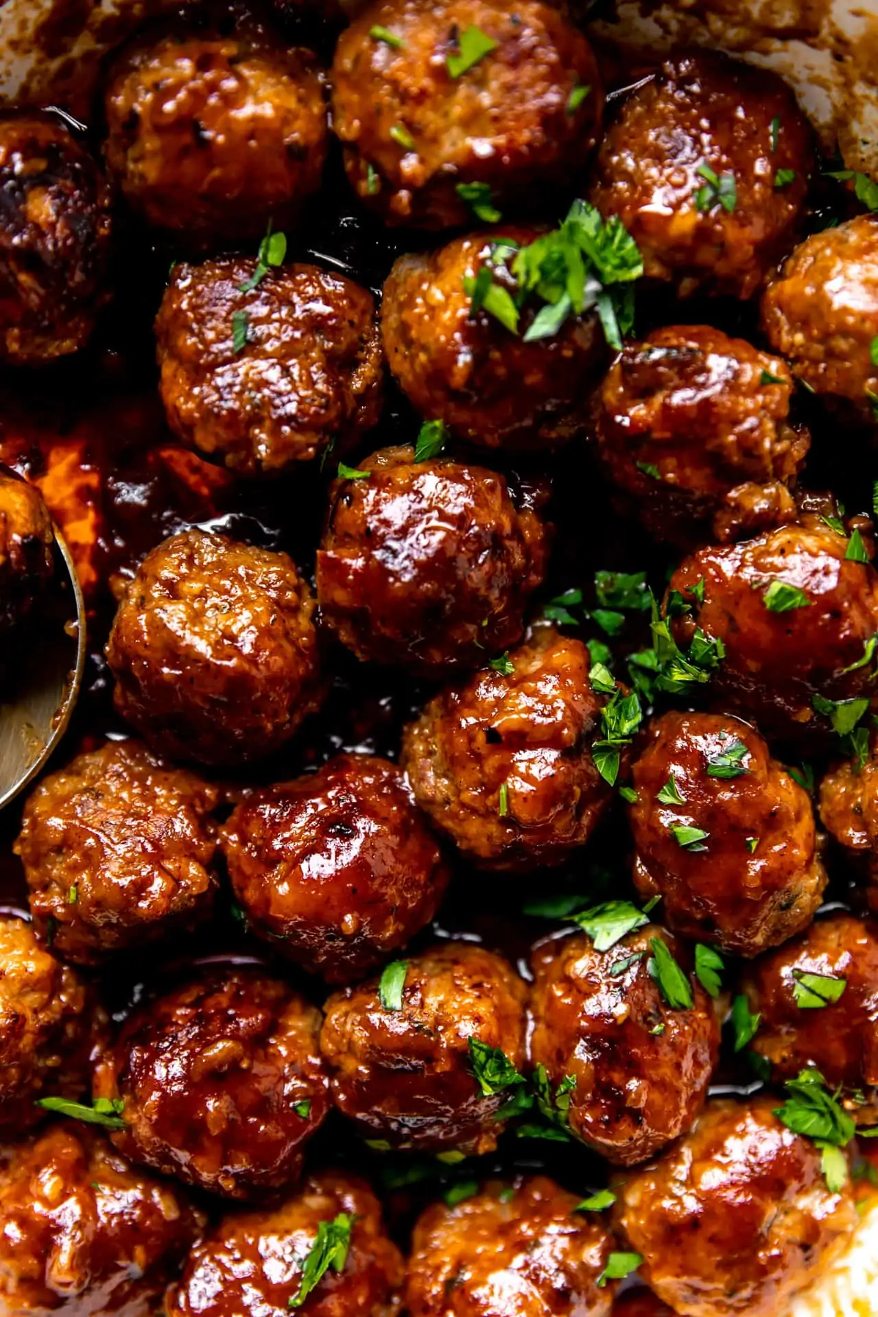 Up close view of a skillet filled with cooked bacon meatballs in a rich bourbon bbq sauce.