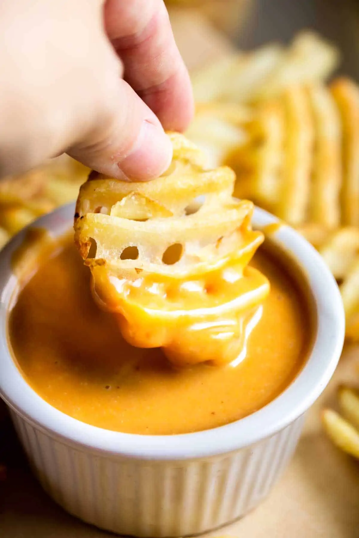 Dipping a waffle fry into a small bowl of homemade Chick Fil A Sauce.