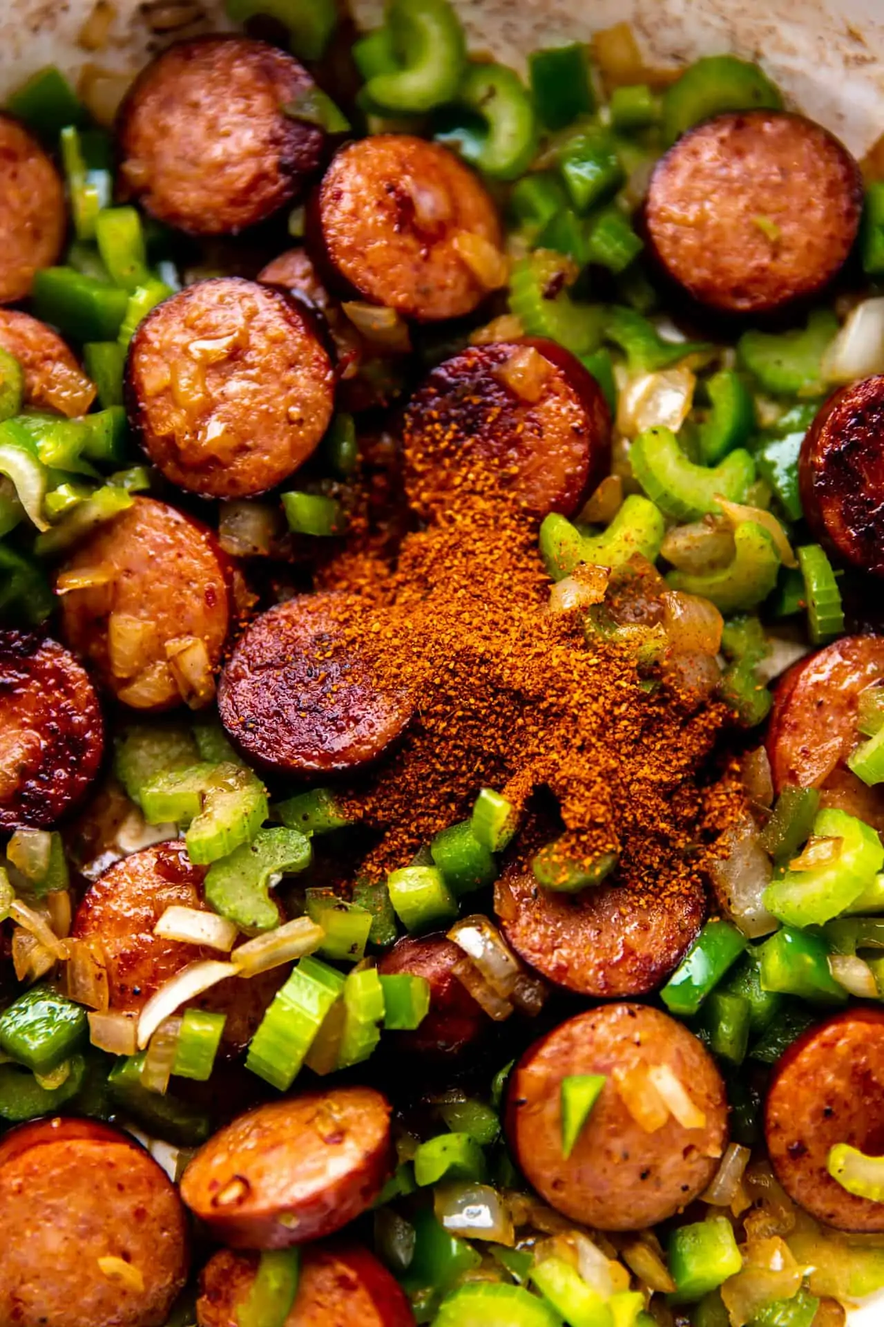 How to make red beans and rice showing cooked sausage and veggies with seasonings added. 