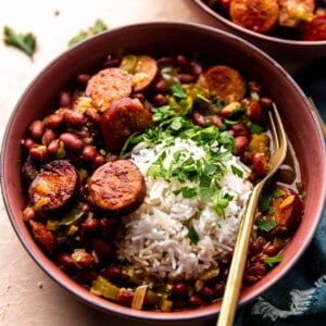 Bowl of red beans and rice served with fresh parsley and a spoon.