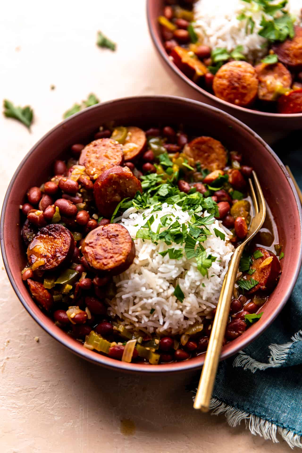 Bowl of red beans and rice served with fresh parsley and a spoon.