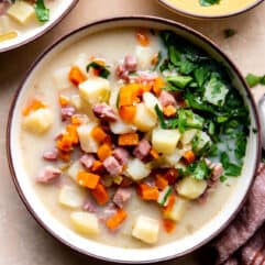 Bowl of ham and potato soup topped with fresh parsley.