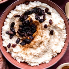 Bowl of creamy rice pudding topped with raisins and a sprinkle of cinnamon.