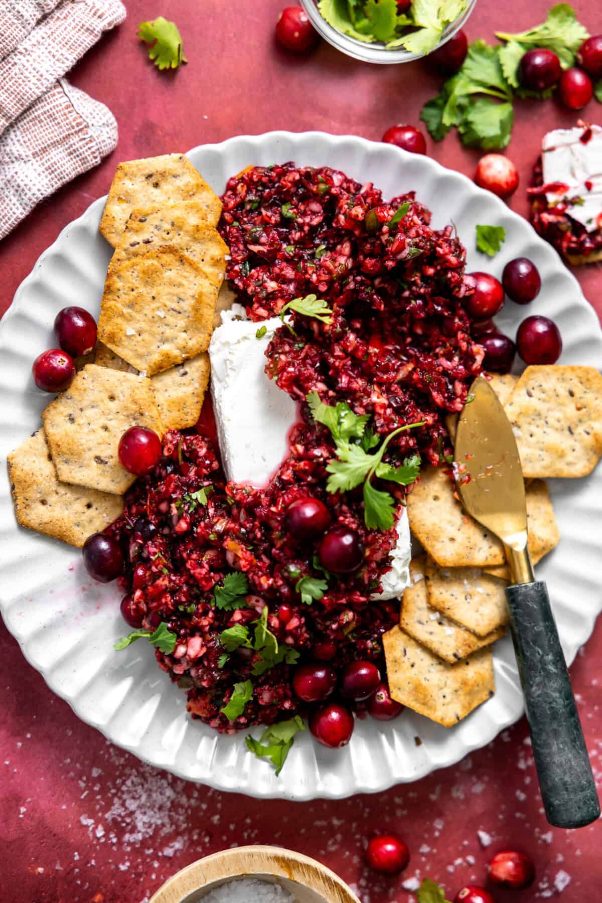 Cranberry Salsa served on a plate over cream cheese with crackers. 