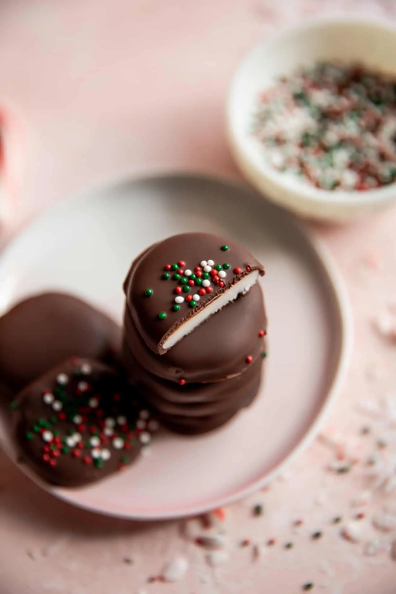 Stack of homemade peppermint patties some with red white and green sprinkles. 