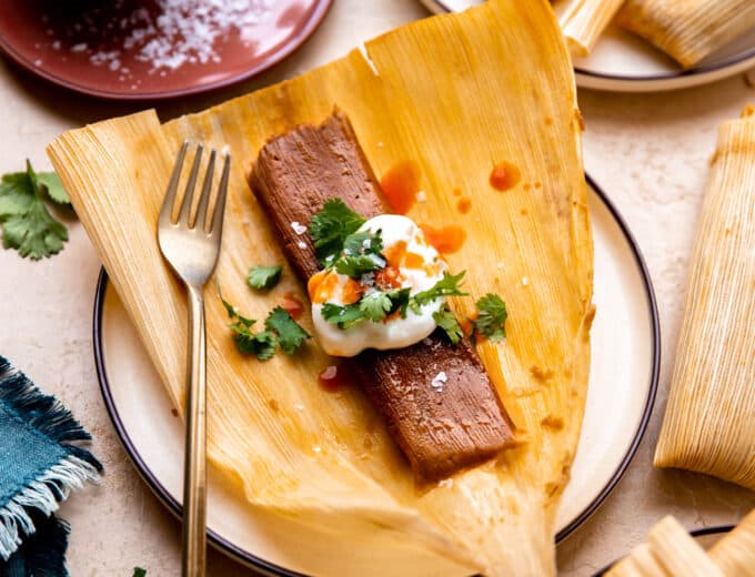 Pork tamales topped with sour cream, cilantro and hot sauce.