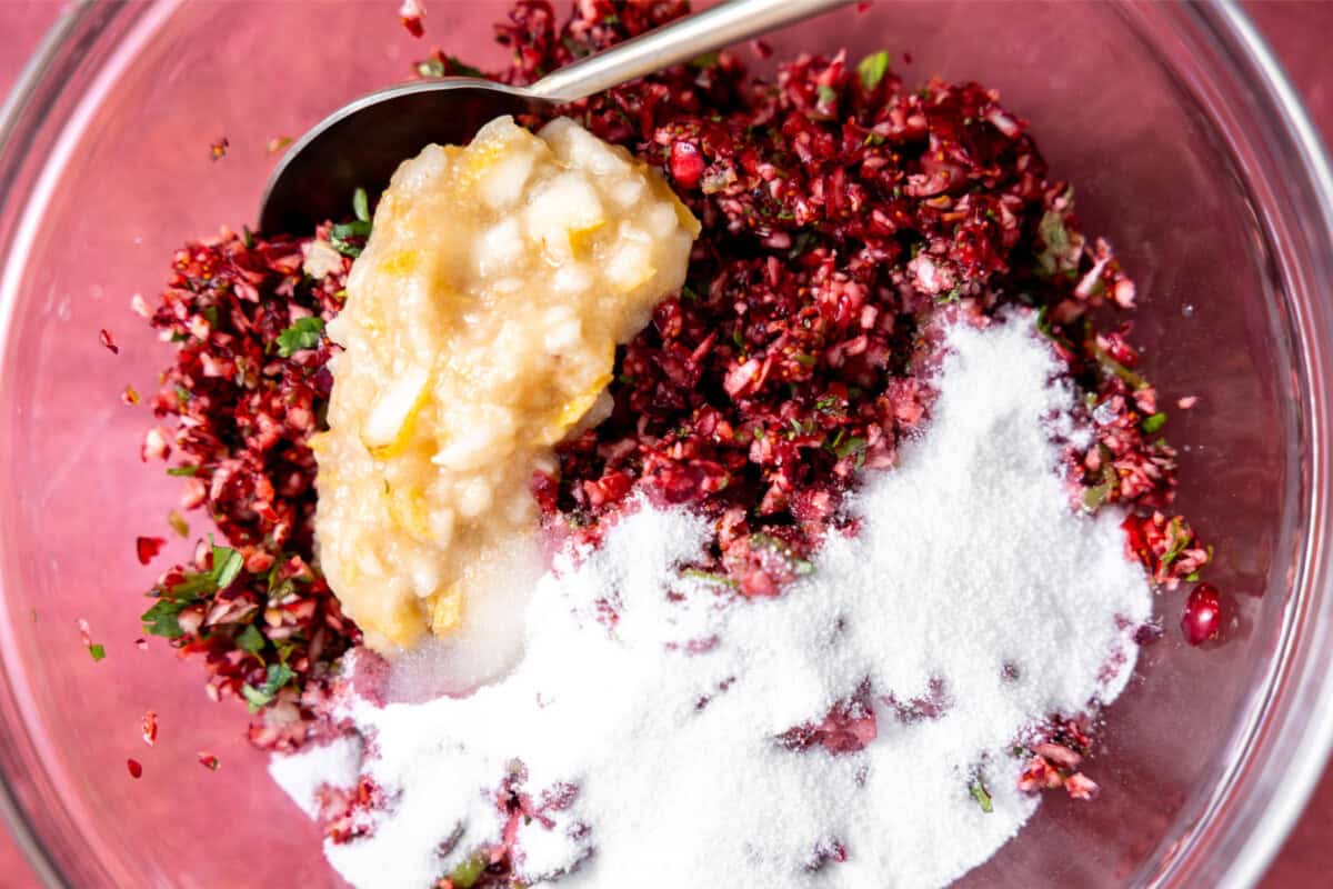 Adding blended pear and sugar to cranberry salsa. 