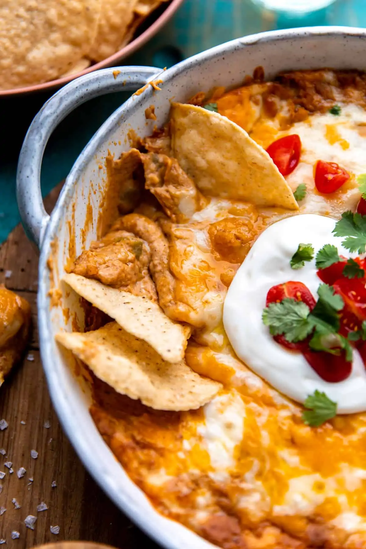 Up close view of bean dip being dished up with tortilla chips. 