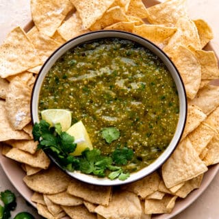 Bowl of homemade salsa verde surrounded by tortilla chips.