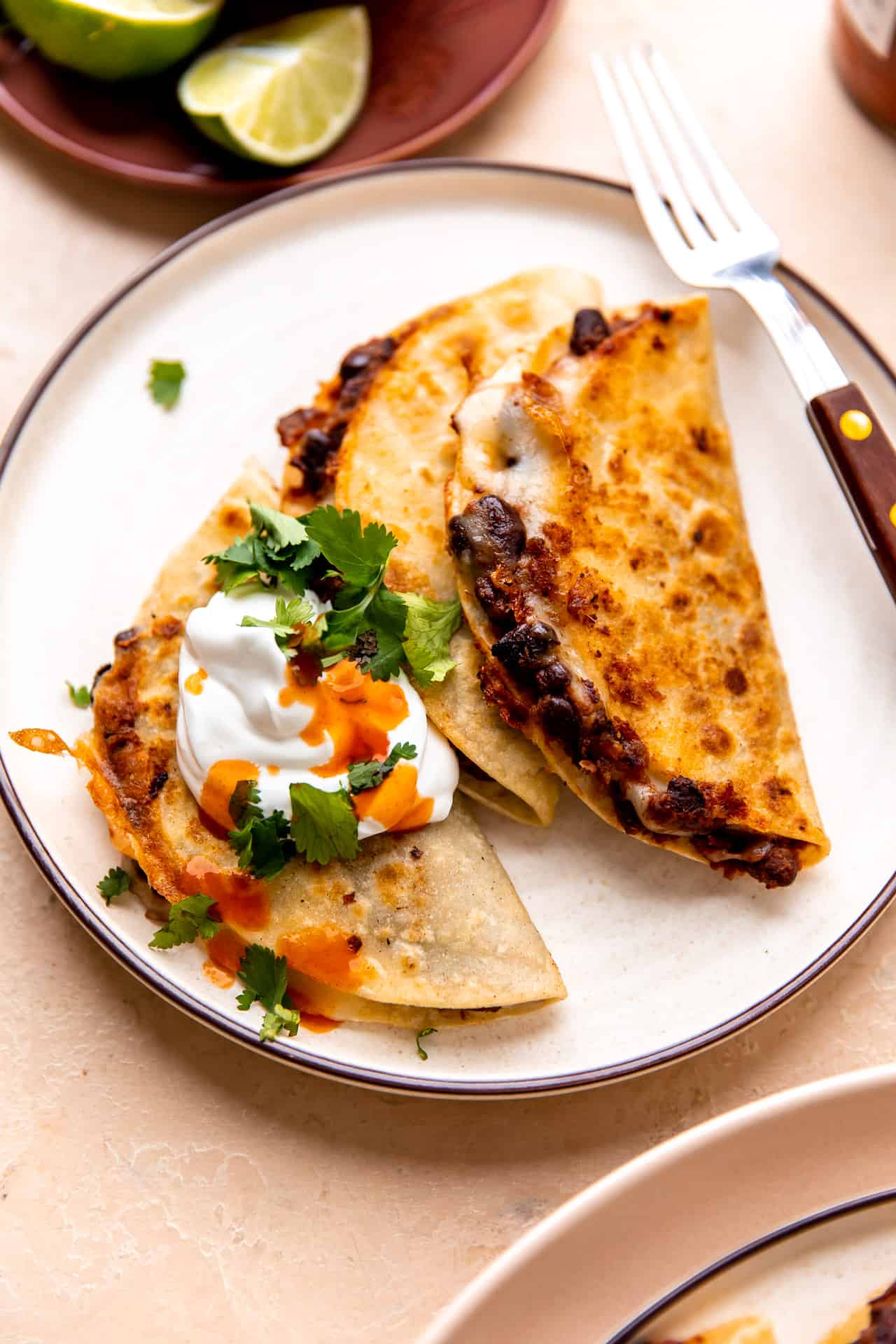 Crispy black bean tacos served with sour cream and hot sauce on top.