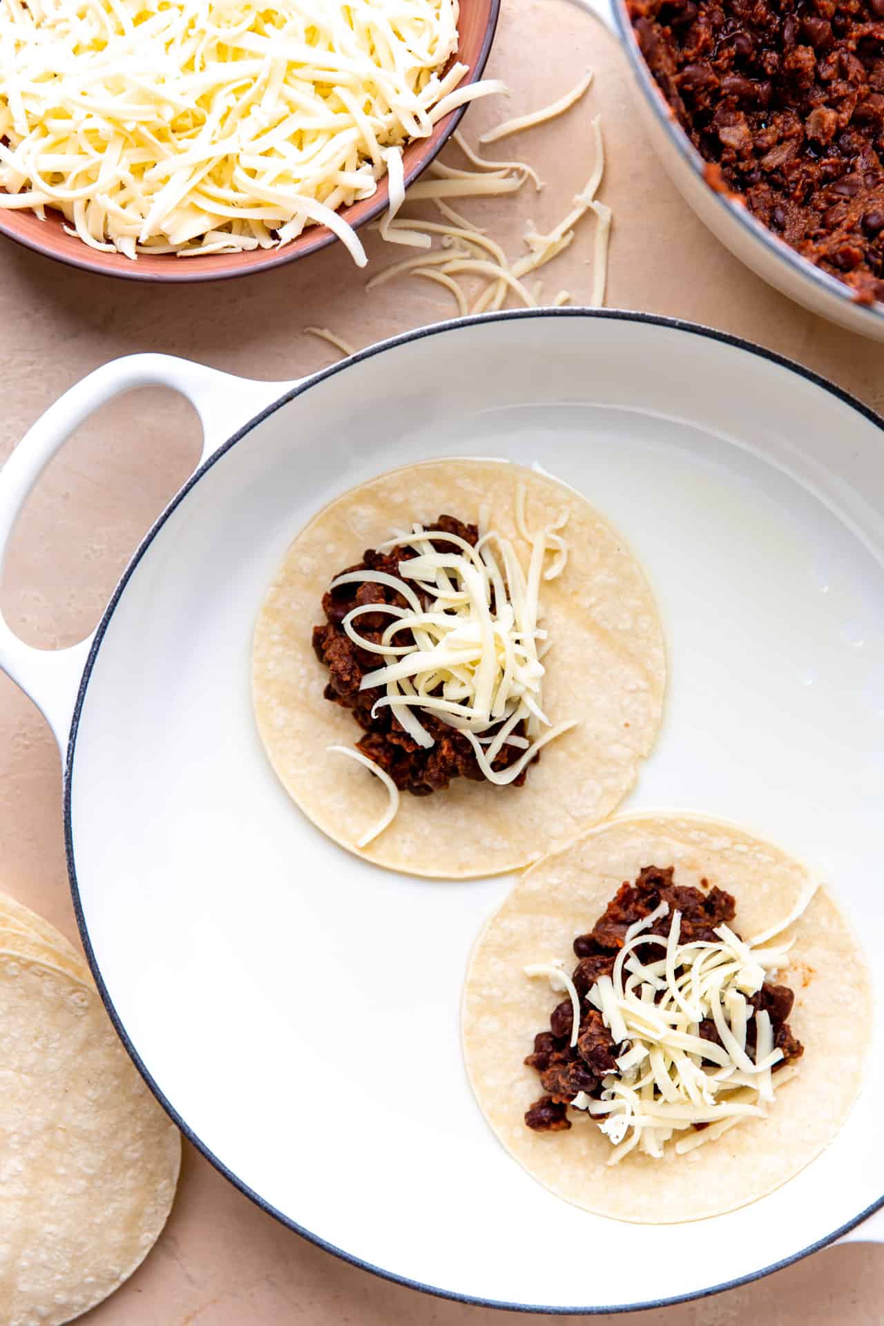 Frying corn tortillas with black bean taco filling and shredded cheese.