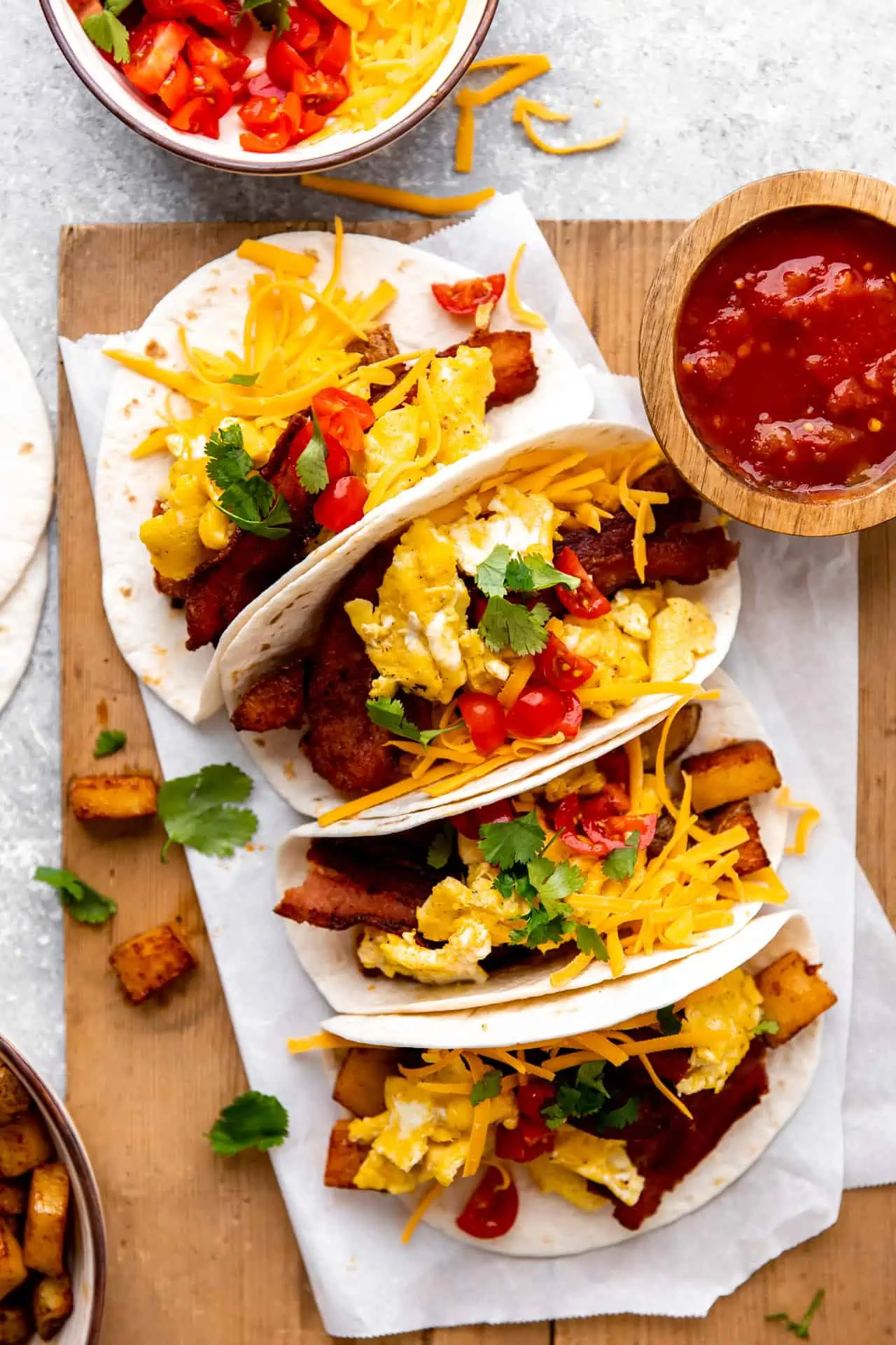 Tray of Breakfast tacos loaded with eggs, bacon and potatoes served with salsa.