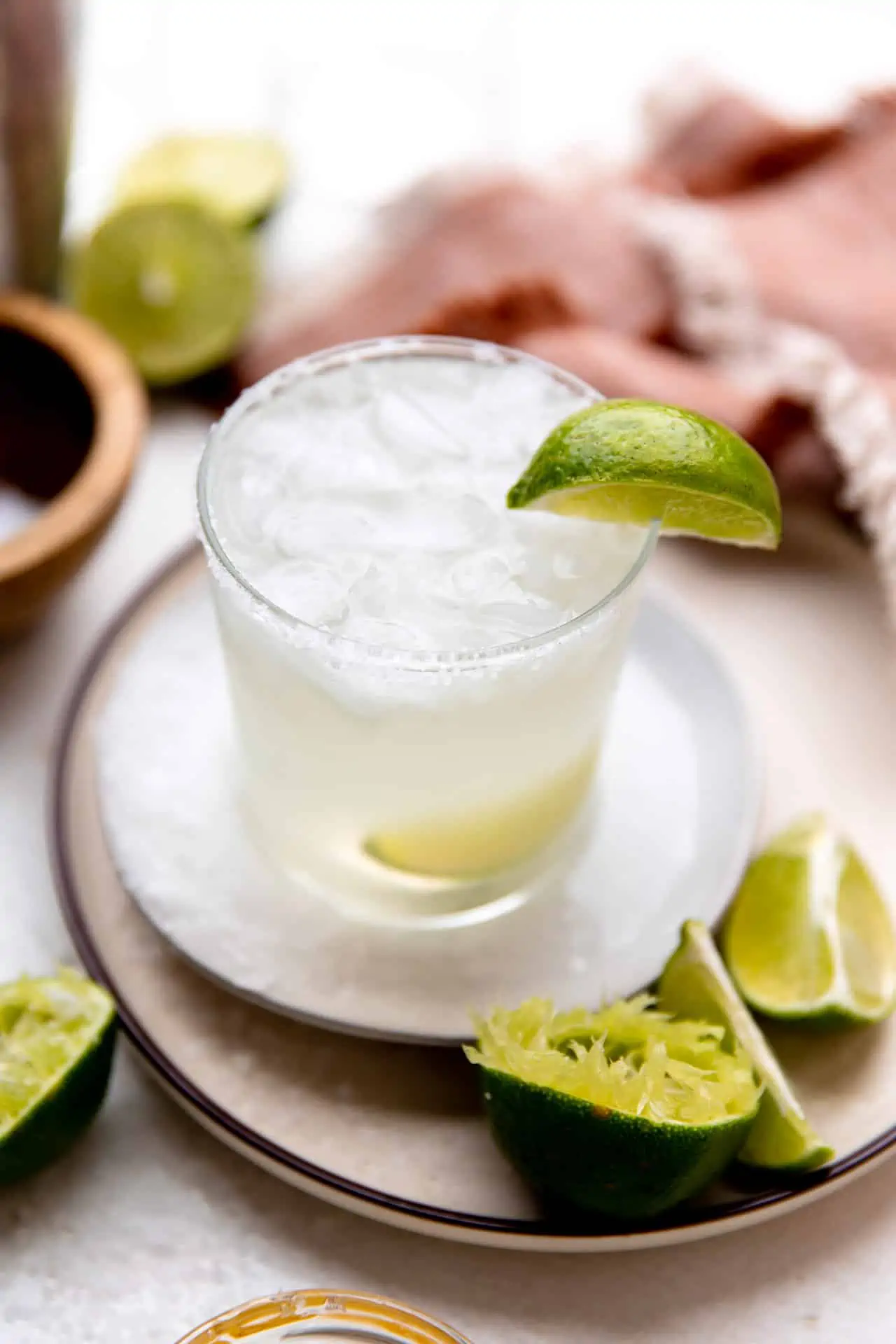 Classic, lime margarita served on the rocks in a glass garnished with a lime wedge.