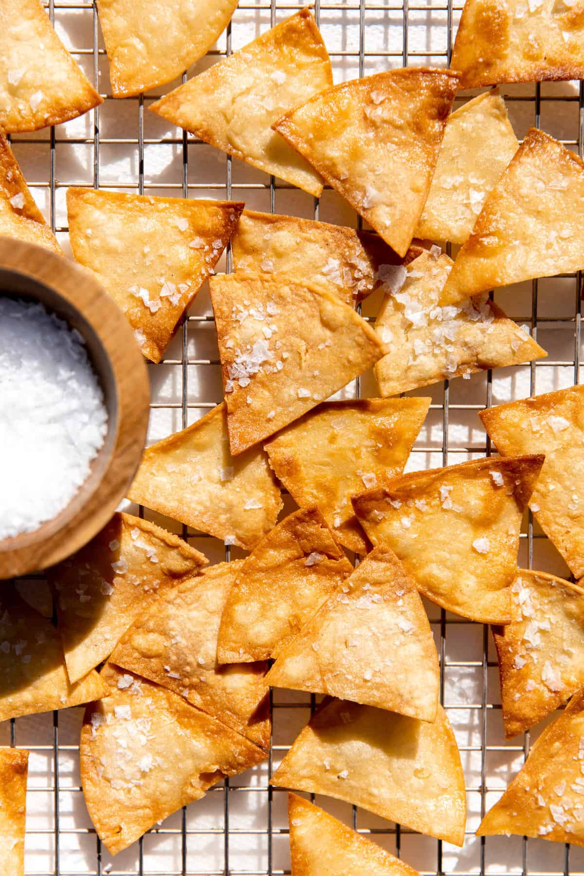 Tortilla chips after being fried and laid on a wire rack to cool.