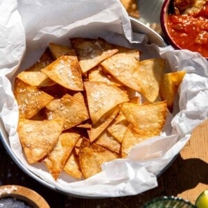 Basket of homemade salted tortillas chips served with salsa and guacamole.