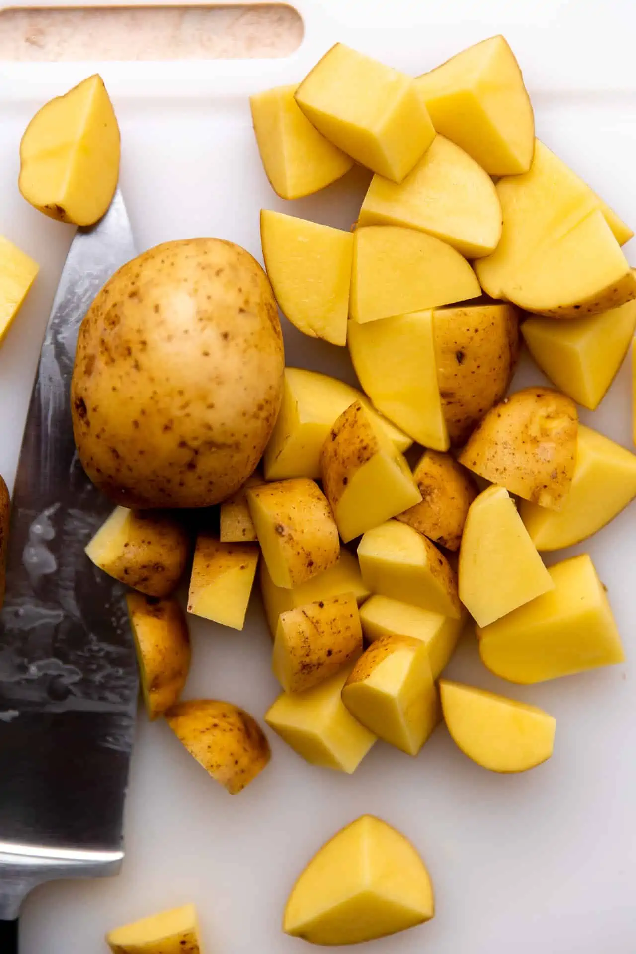 Gold potatoes being diced into 1 inch cubes.