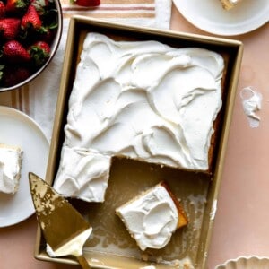Tres Leches cake with slices cut out and being served with strawberries.