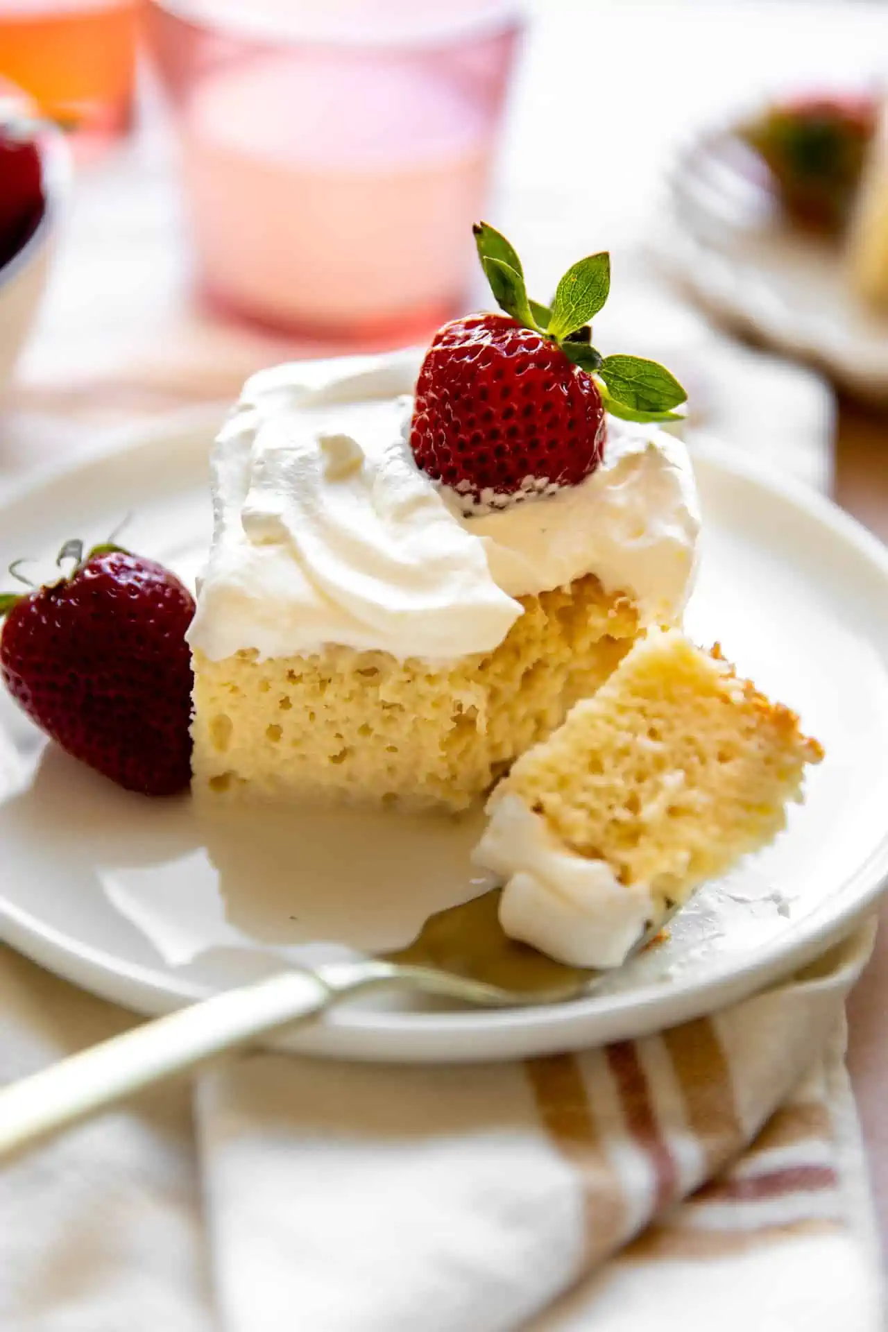 Tres Leches cake topped with fluffy whipped cream and fresh strawberries. 