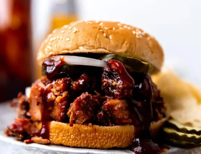 Smoked BBQ Brisket sandwich made with sauce, pickles and sliced onion. Served with chips