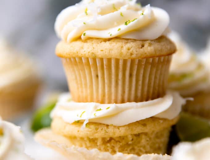 Stacked coconut lime cupcakes topped with coconut cream cheese frosting.