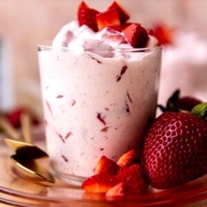 Cup of fresas con crema served with extra strawberries on top and side.