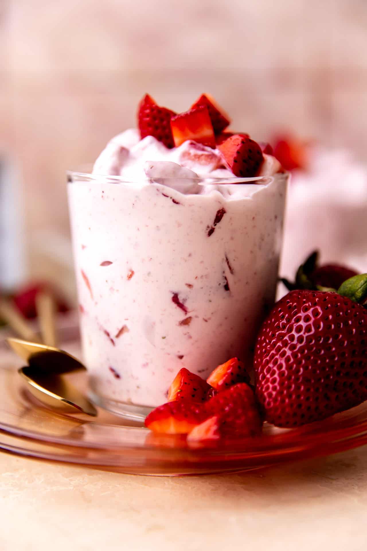 Cup of fresas con crema served with extra strawberries on top and side. 