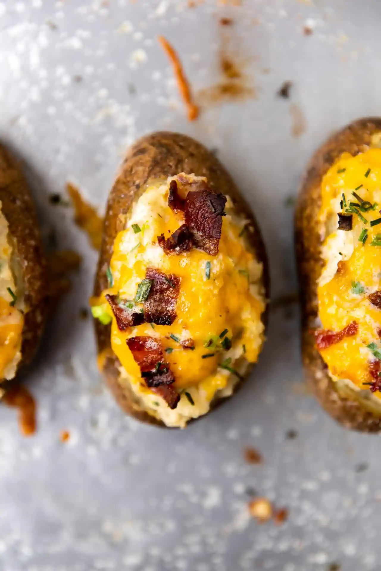 Overhead view of twice baked potatoes showing melty cheese and crispy bacon on top. 