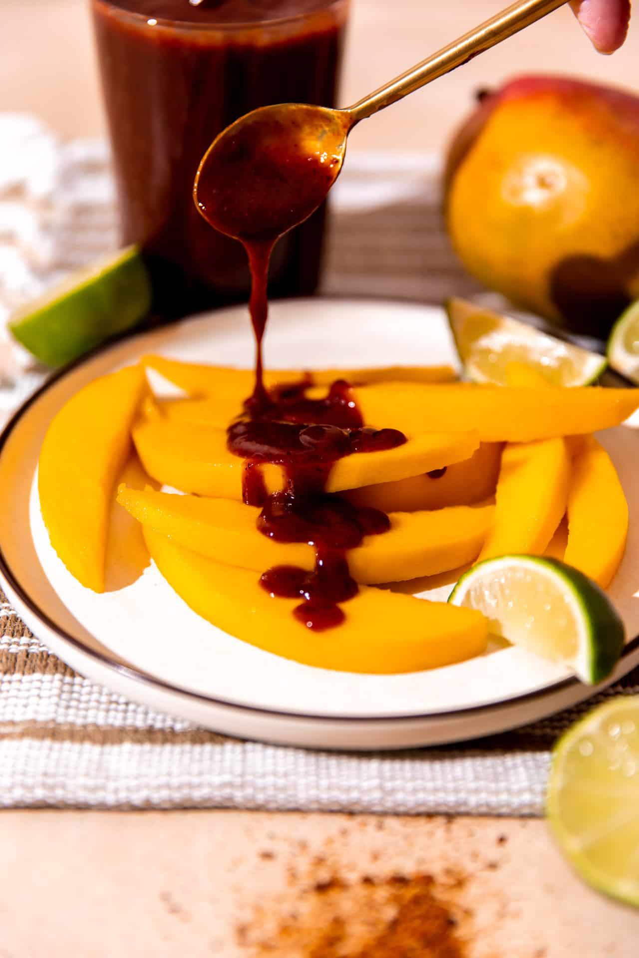 Homemade Chamoy sauce being drizzled over the top of fresh sliced mango.