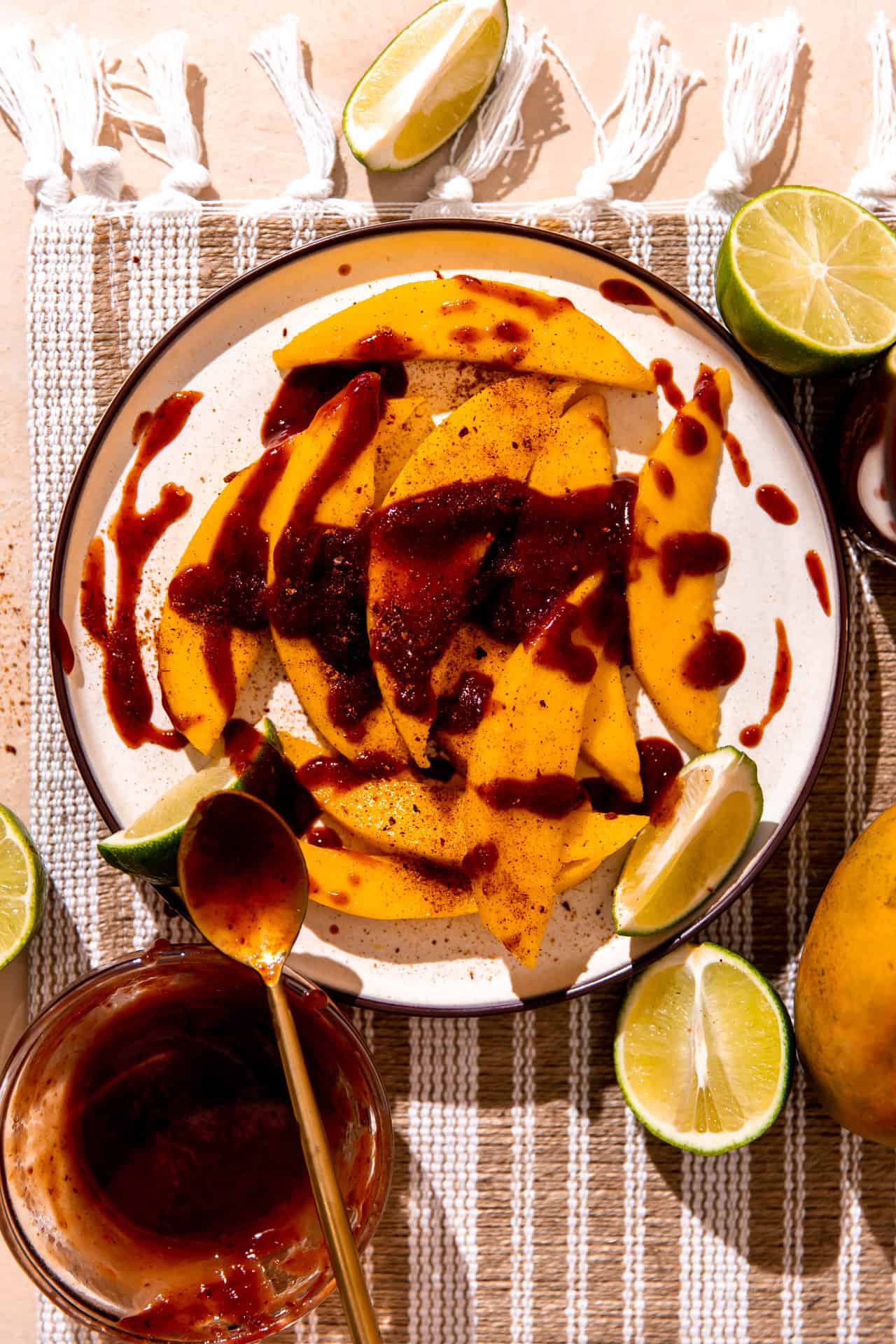 Plate with sliced mango, drizzled in chamoy and sprinkled with tajin. 