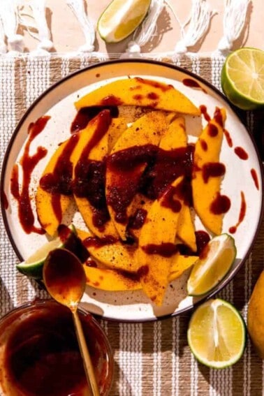 Plate with sliced mango, drizzled in chamoy and sprinkled with tajin.