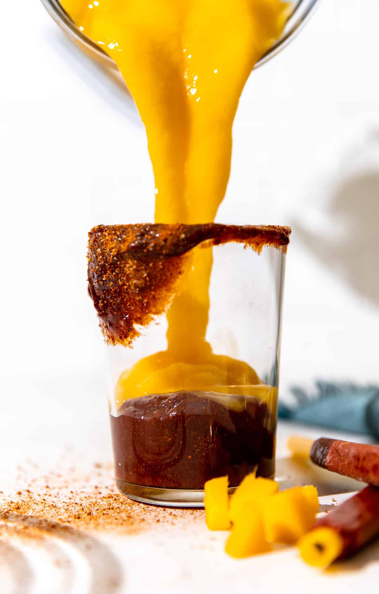 Pouring mango smoothie over chamoy for a mangonada. 