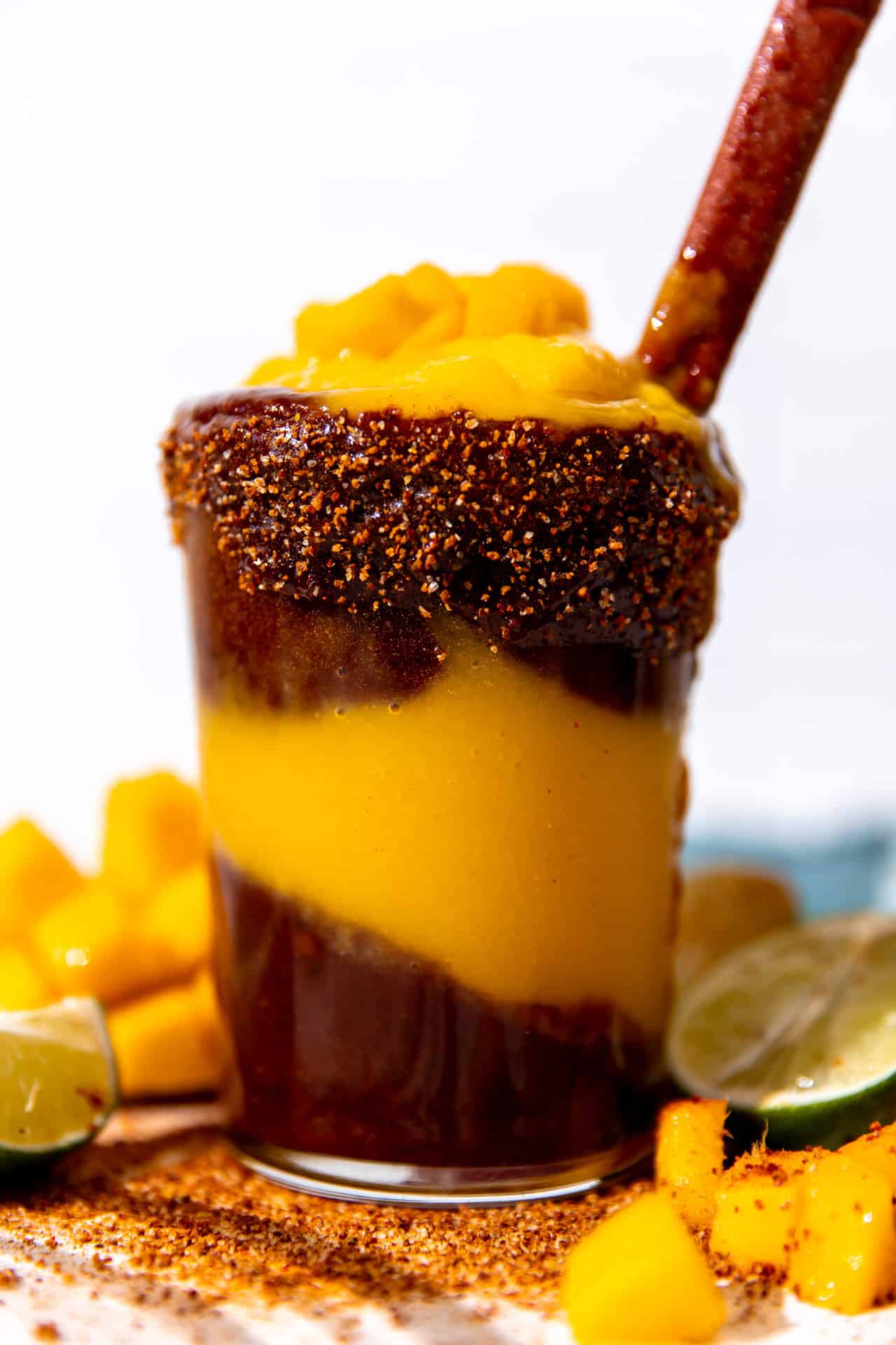 Homemade mangonada topped with fresh diced mango and served with a tamarindo straw. 