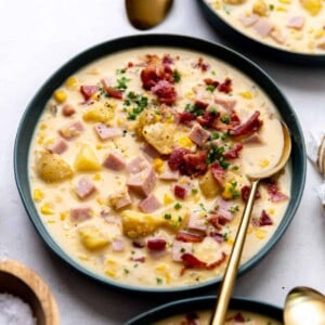 Bowl of corn chowder topped with crispy bacon and garnished with fresh chives.