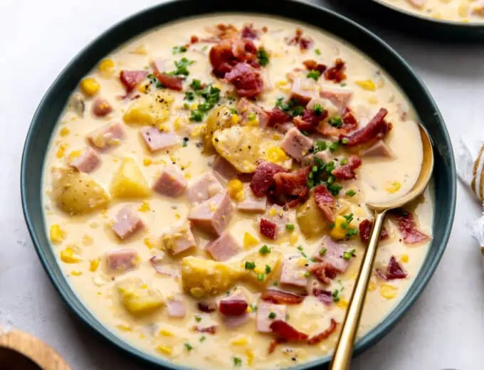 Bowl of corn chowder topped with crispy bacon and garnished with fresh chives.