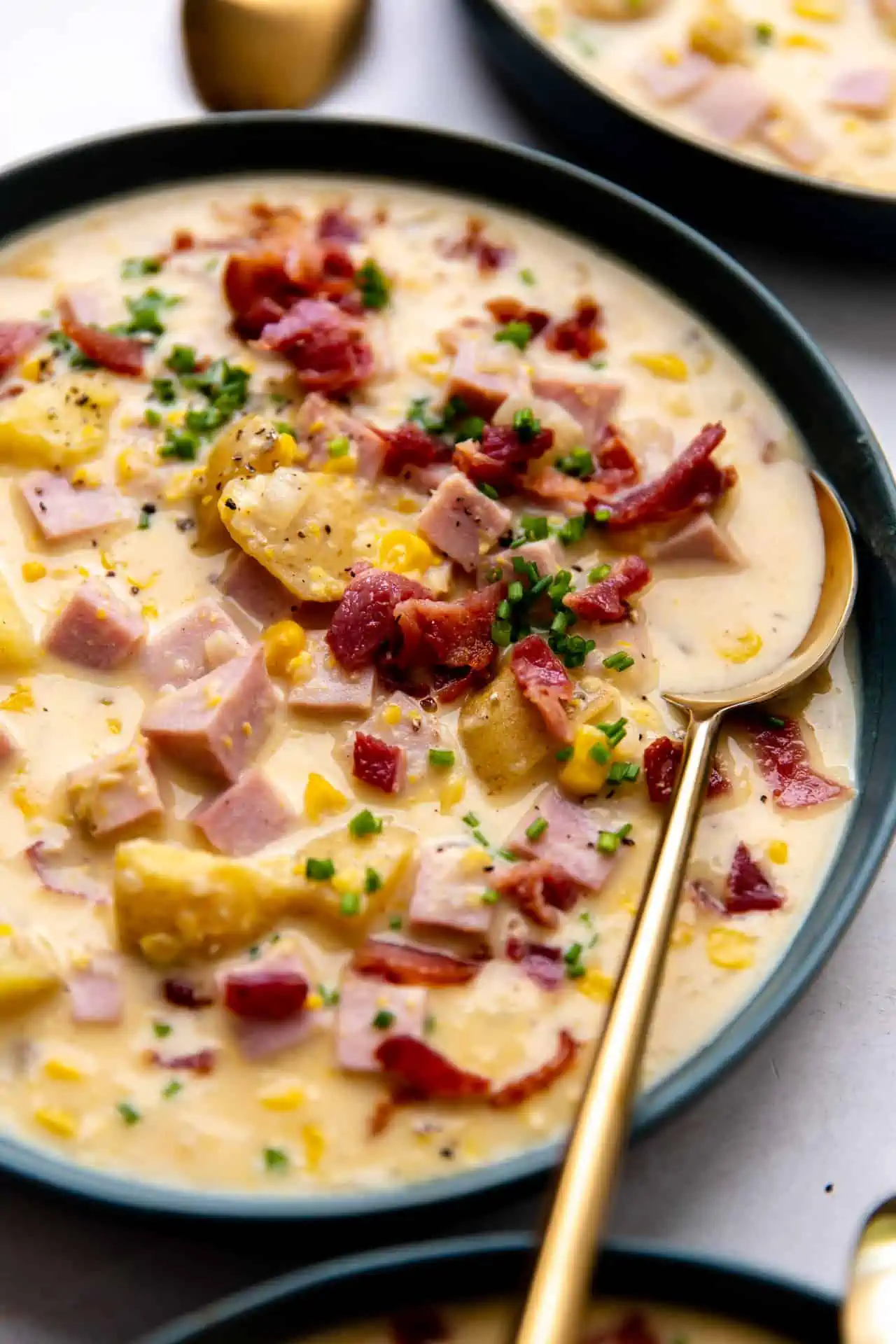 Up close view of a bowl of corn chowder topped with crisp bacon and fresh chives. 