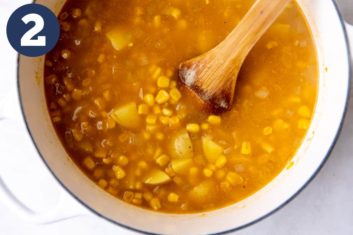 Broth with potatoes and corn in a dutch oven.