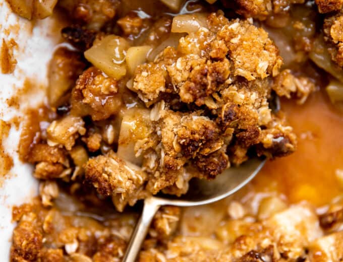 Baked apple crisp being served with a large spoon.
