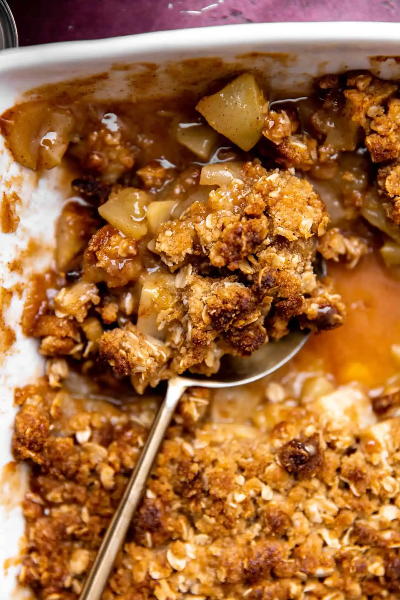 Baked apple crisp being served with a large spoon.