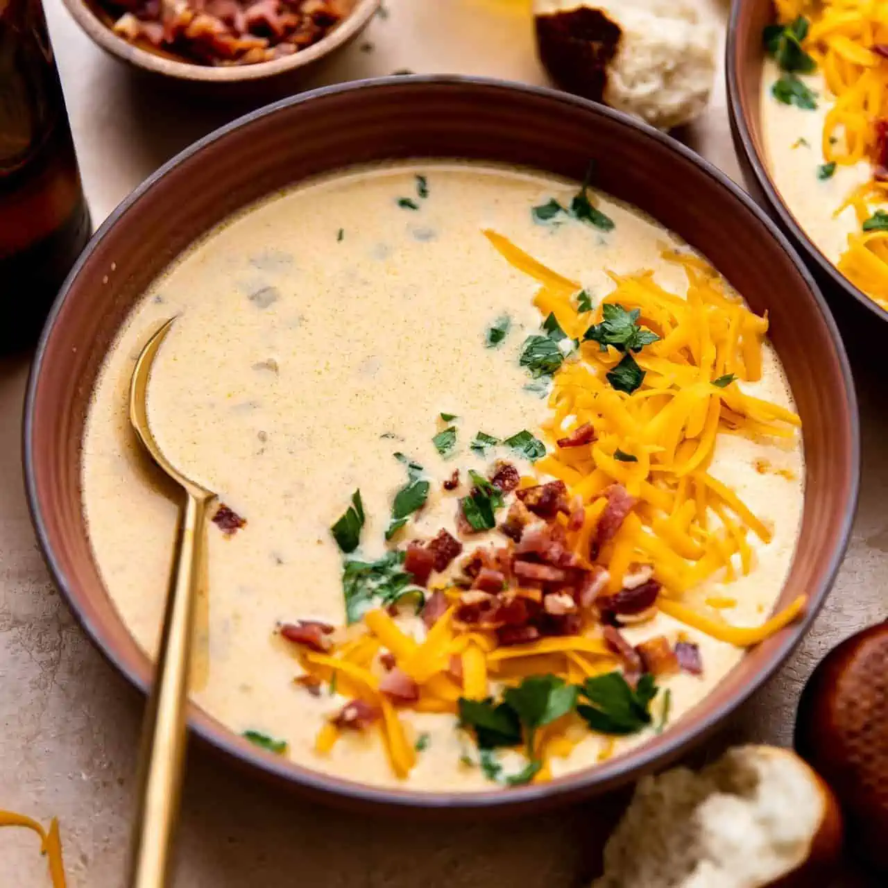 Bowl of beer cheese soup topped with shredded cheese and crumbled bacon.