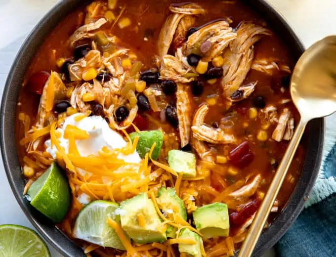 Bowl of chicken enchilada soup topped with cheese, sour cream and avocado.