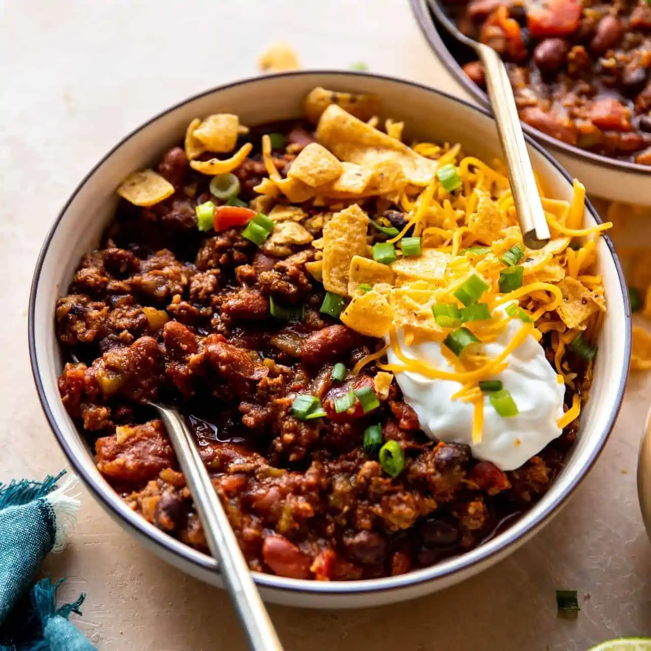 Bowl filled with homemade classic chili topped with sour cream, cheese, chips and diced green onion.