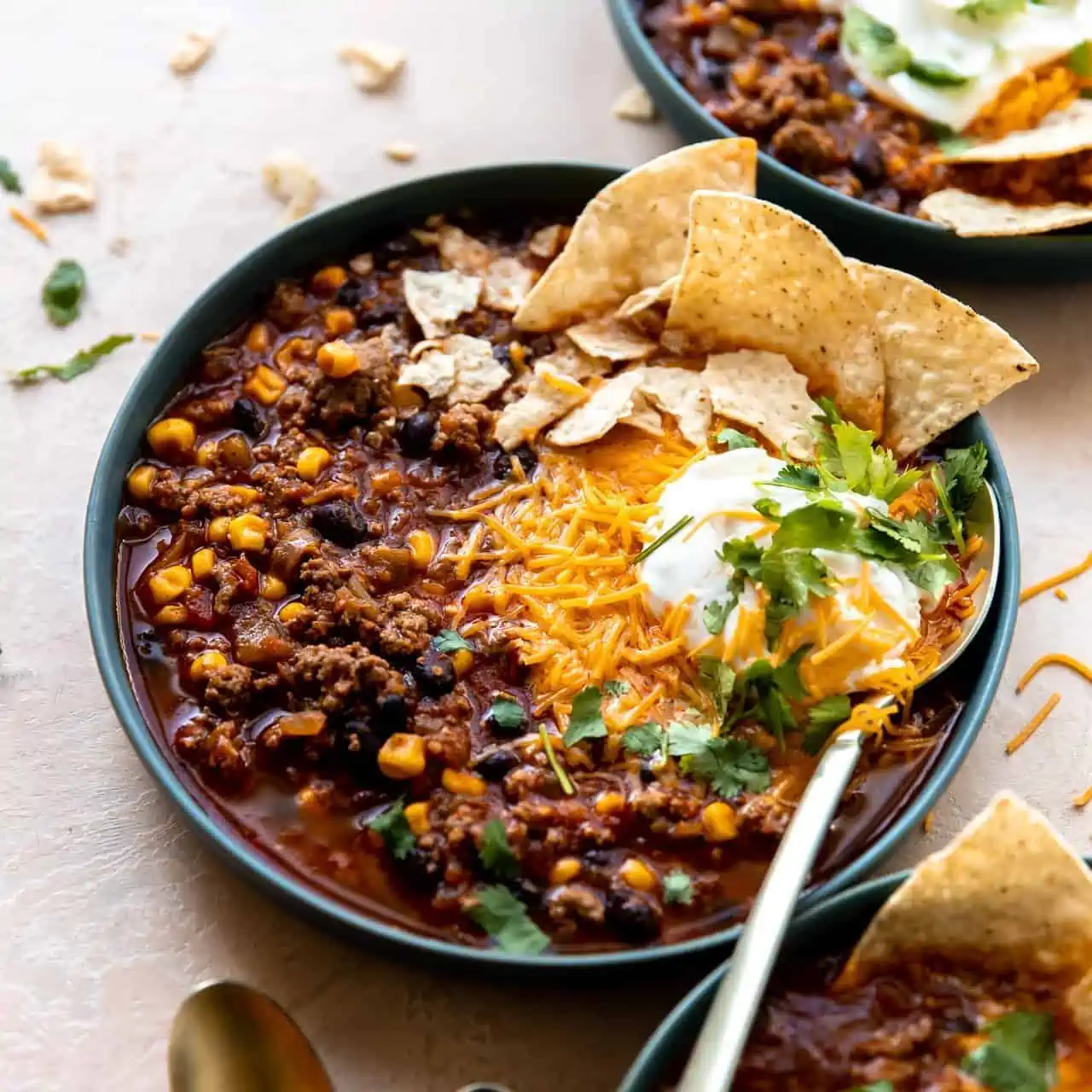 Bowl of taco soup served with cheese, sour cream and tortilla chips.