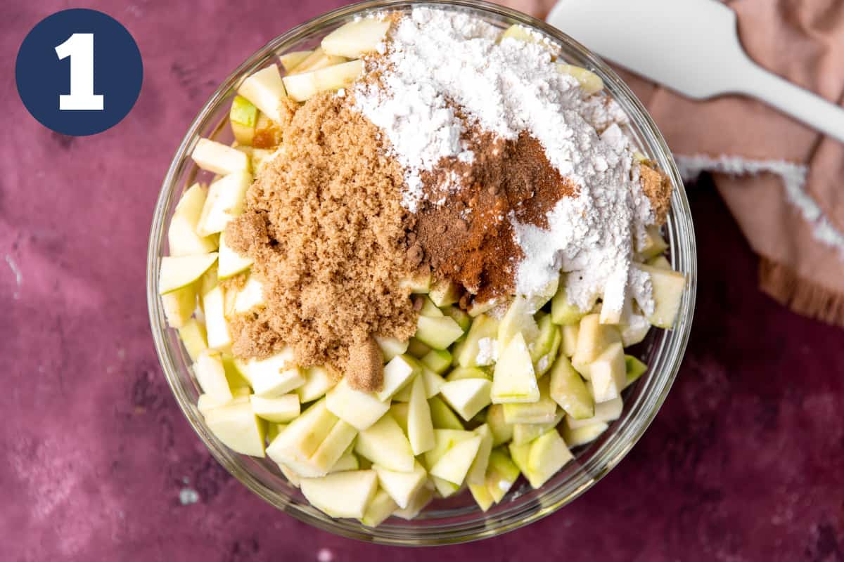 Apples being mixed with brown sugar and spices for making apple crisp. 