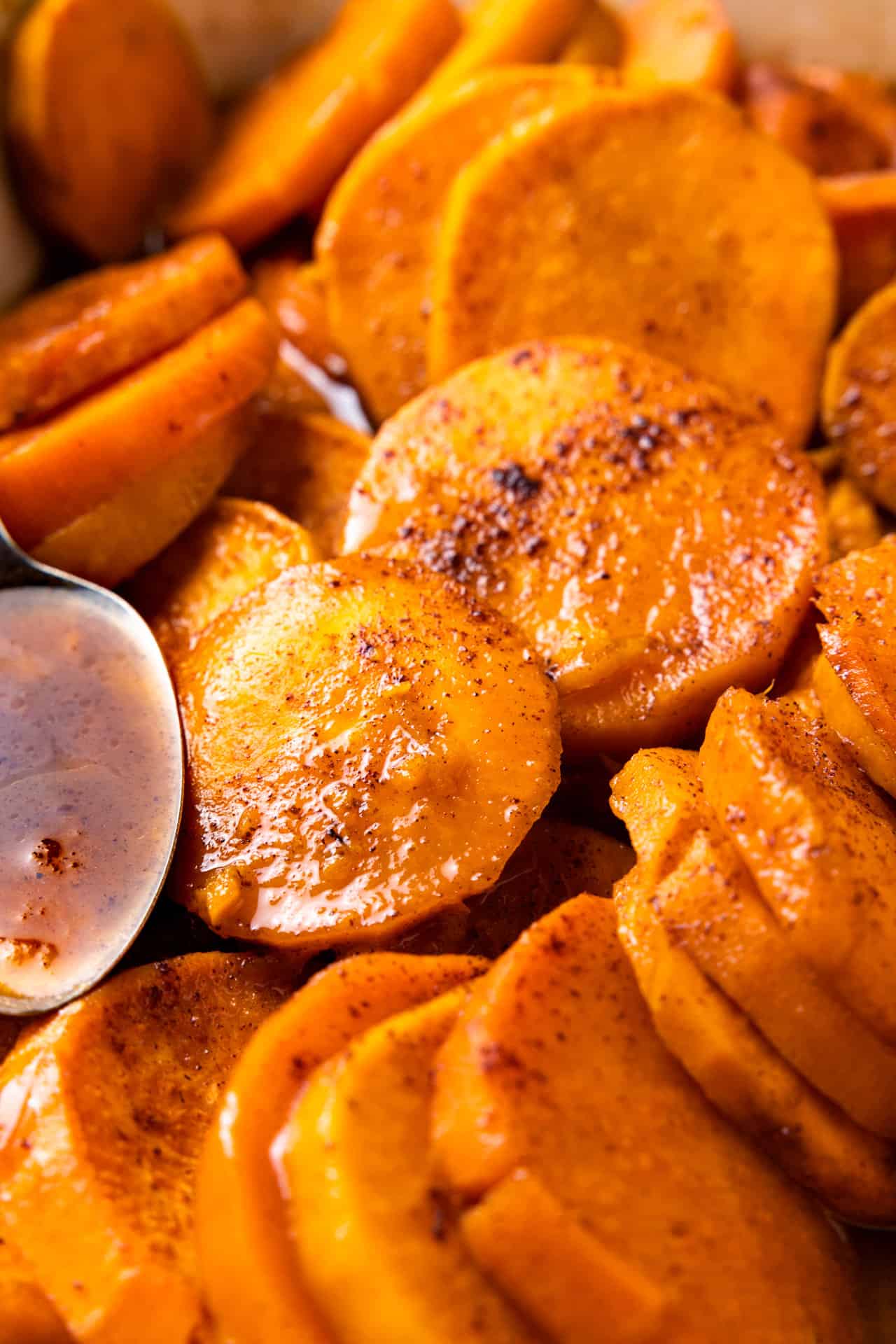 Up close of baked, candied sweet potatoes coated with a sweet, spice syrup. 