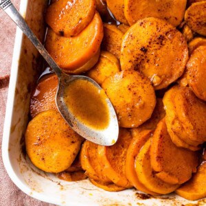 Baking dish with candied sweet potato and a spoon.