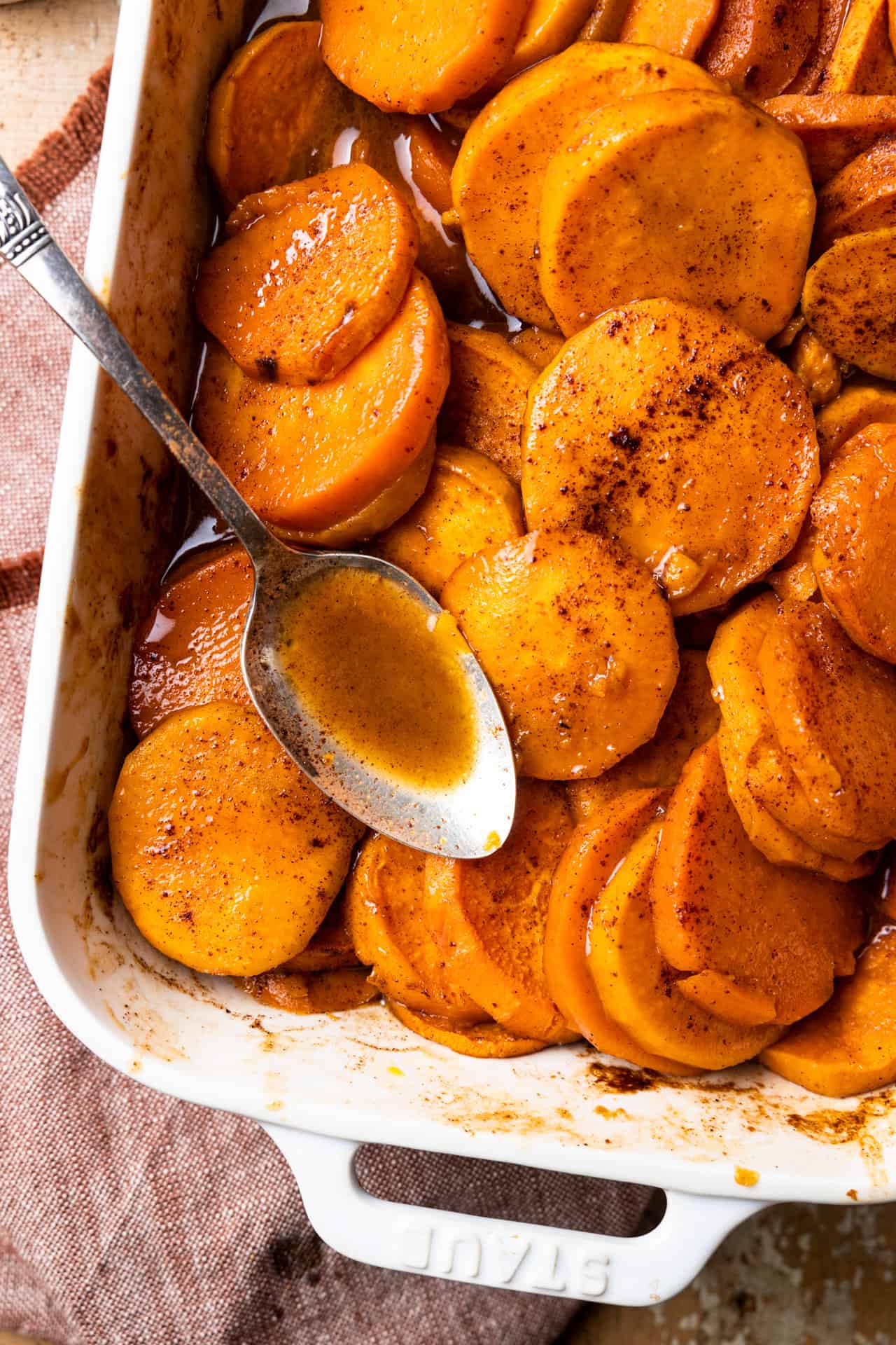 Baking dish with candied sweet potato and a spoon.