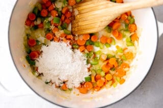Stirring veggies with flour in a dutch oven.